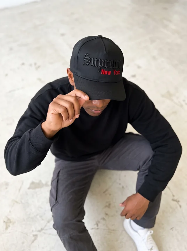 Gorra con bordado negro y rojo, mostrada en modelo. Fotografía ORX-001.